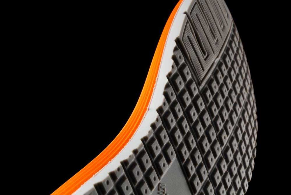 Orange and white sole of an athletic shoe on a black background